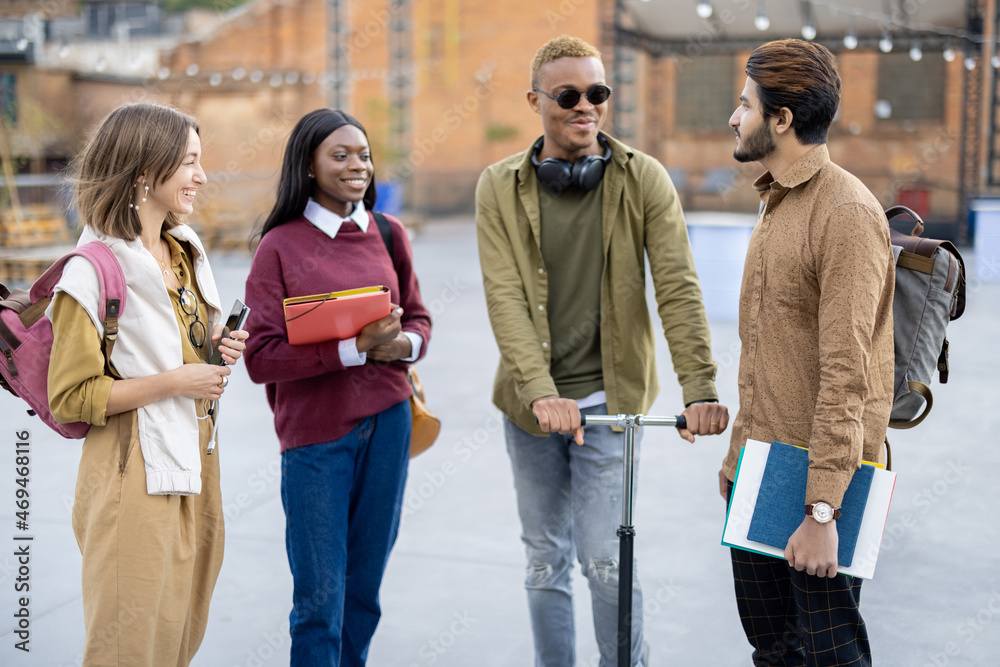 Smiling multiracial students walk together at university campus. Concept of education and learning. 