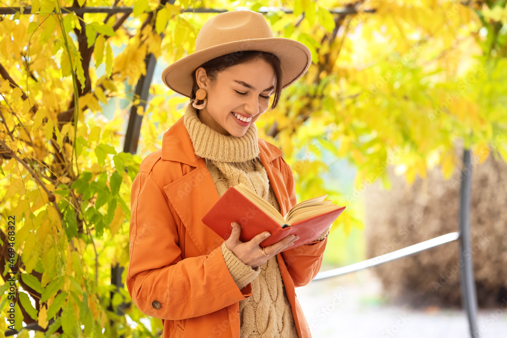 Beautiful woman reading book in autumn park