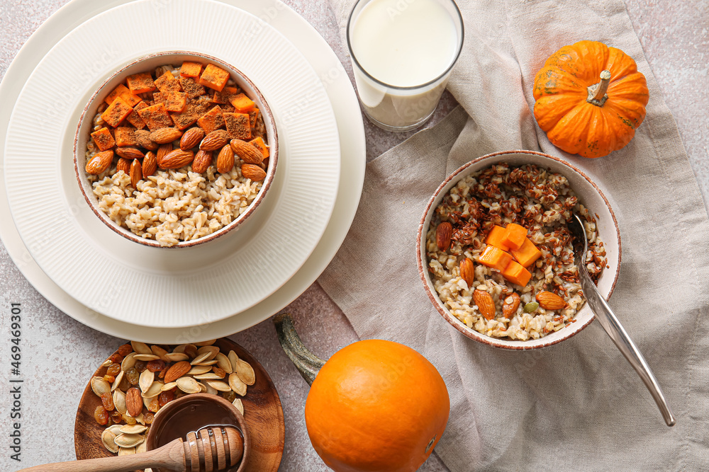 Bowls of tasty oatmeal with pumpkin and almond on light background