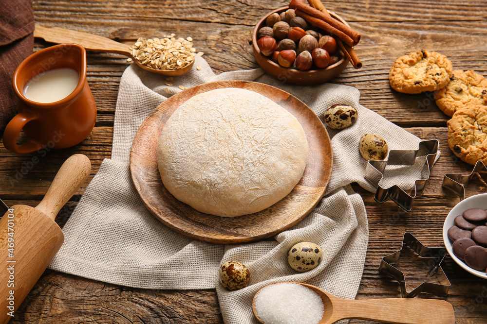 Plate with fresh dough for preparing homemade cookies on wooden background