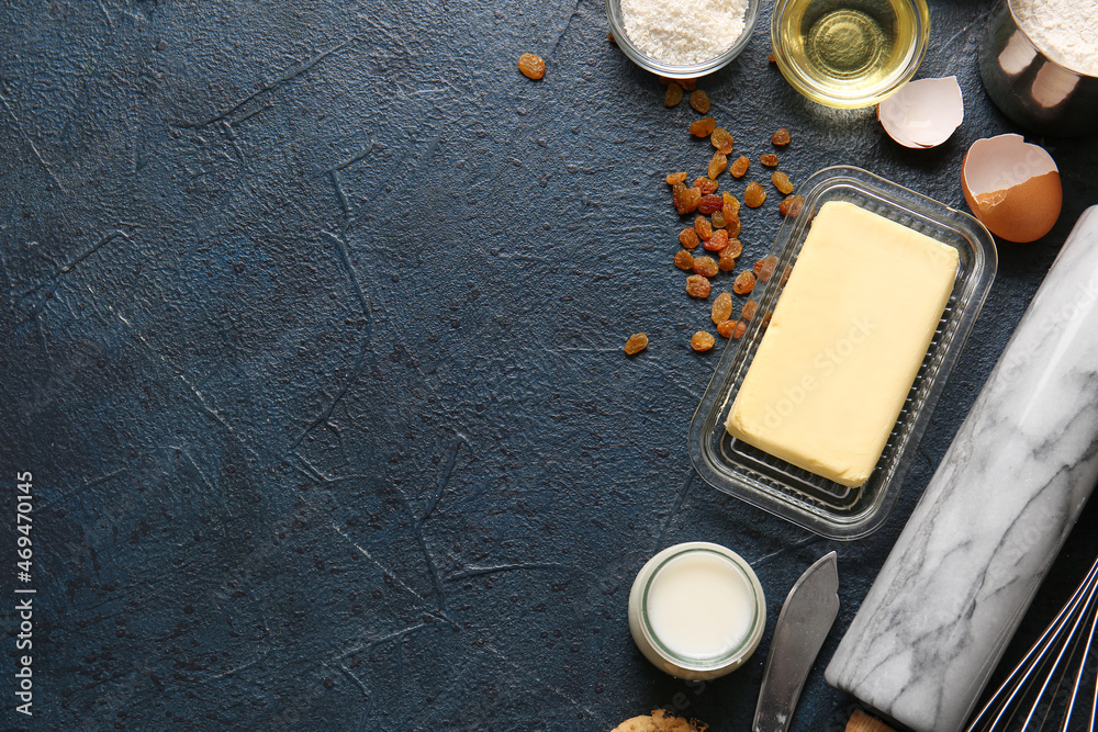 Fresh butter and ingredients for preparing homemade cookies on black background