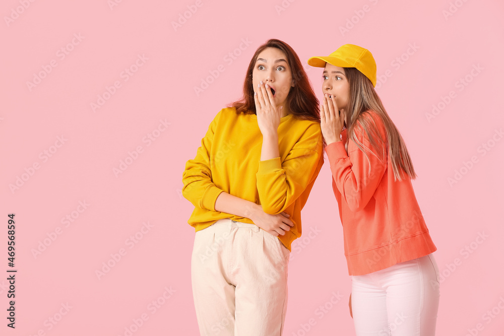 Young gossiping women on color background