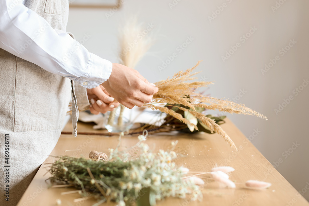 女花艺师在餐桌上用漂亮的干花制作花束，特写