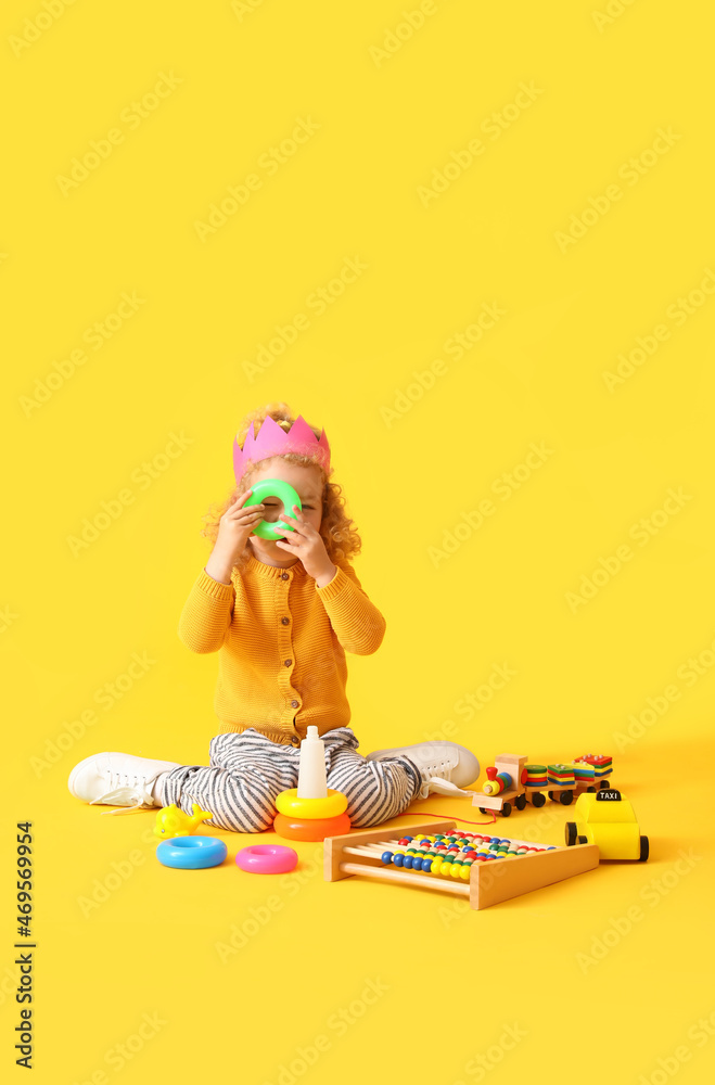 Cute baby girl with toys on color background