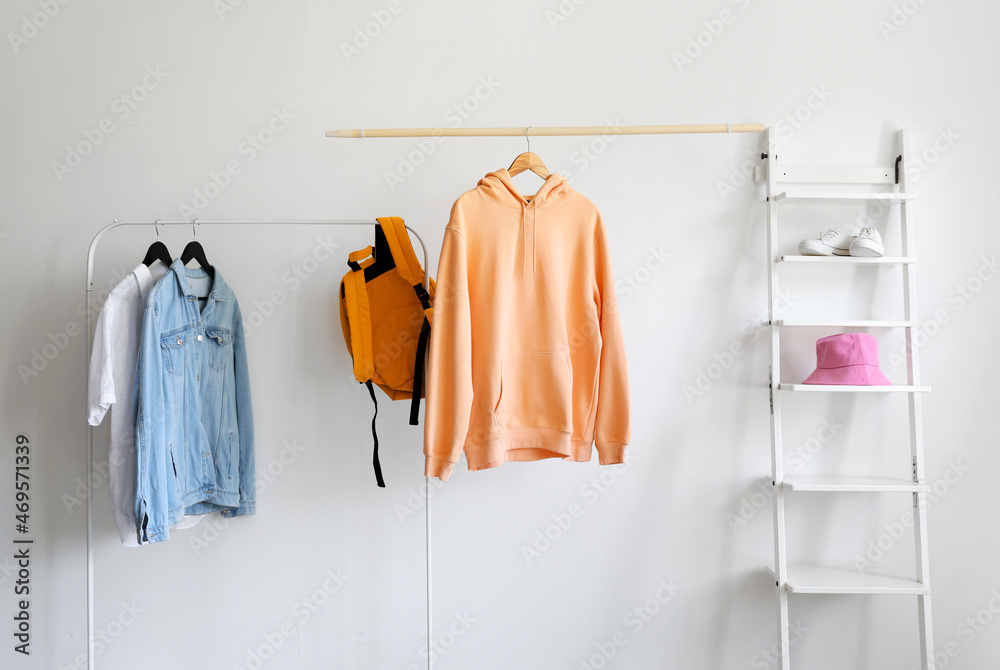 Rack with clothes and shelf unit near light wall