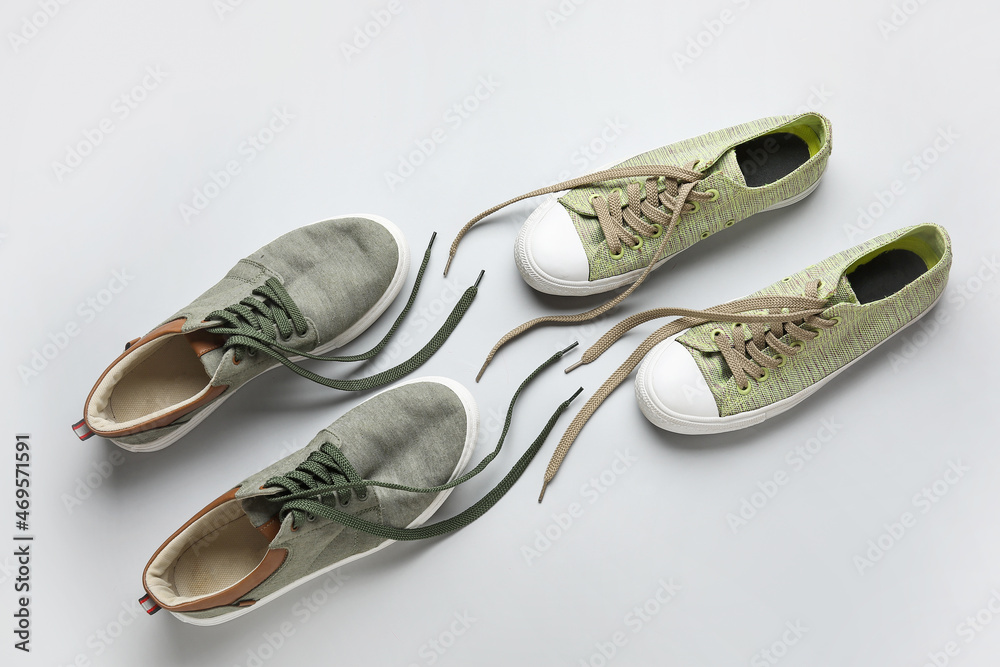 Two pairs of stylish shoes with untied laces on white background