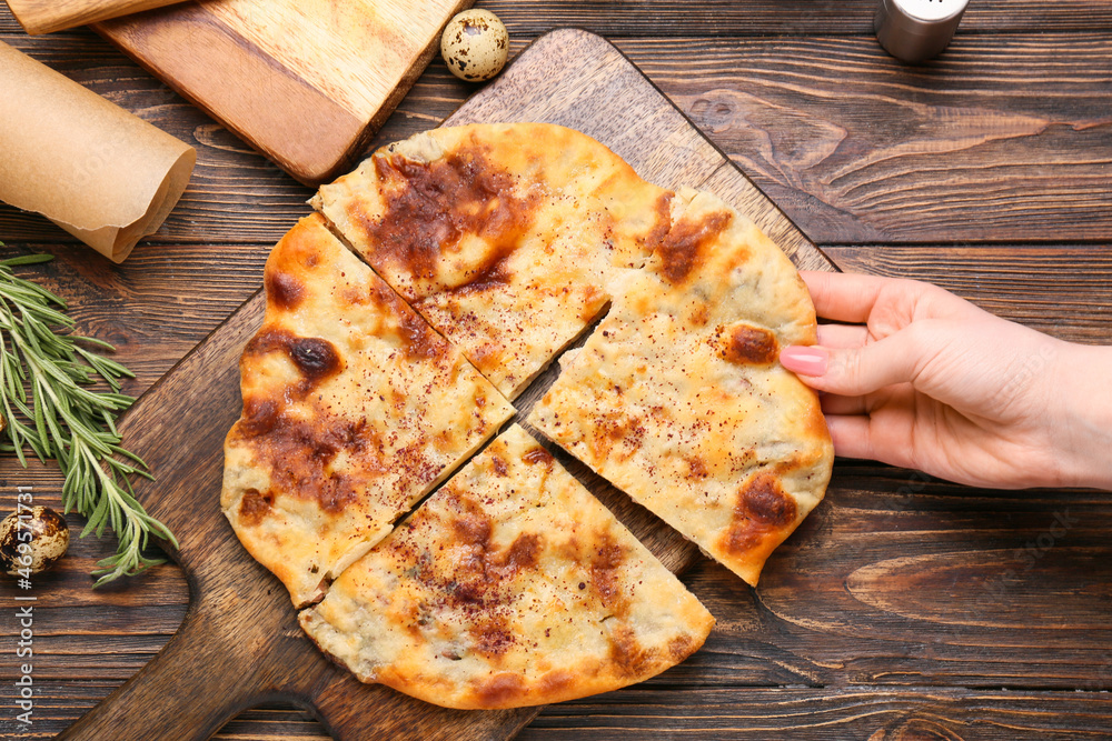 女人在木背景上吃美味的khachapuri