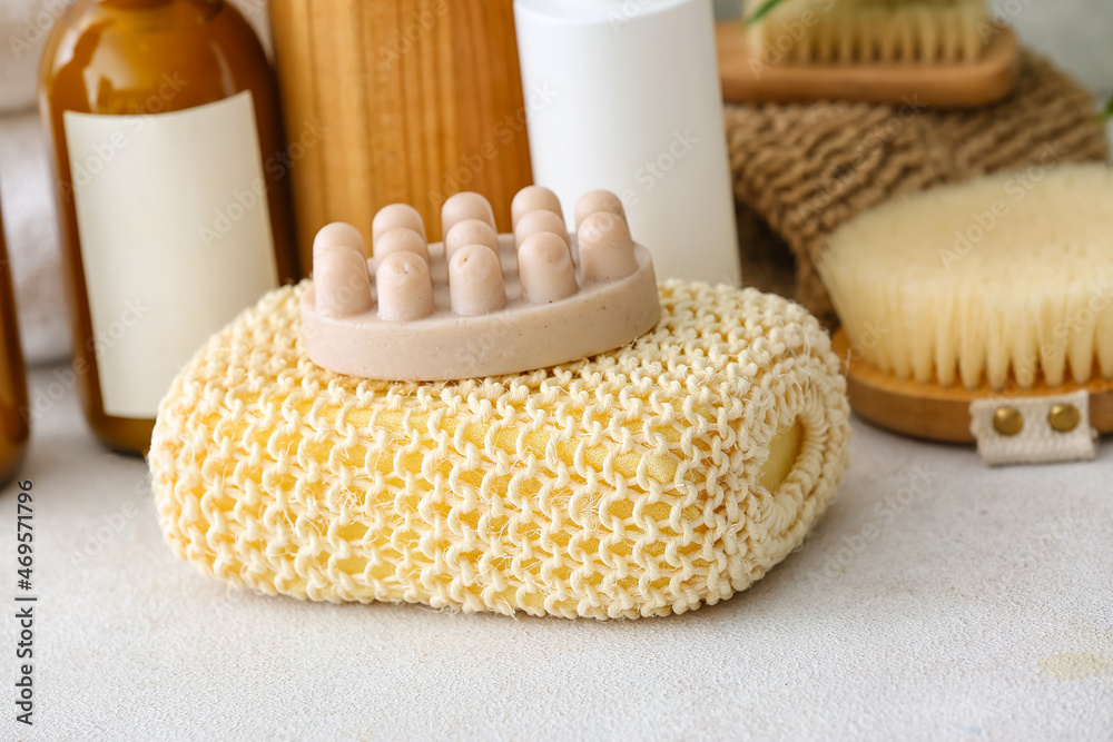 Bath sponge, massage soap bar and bottles of cosmetic products on table, closeup