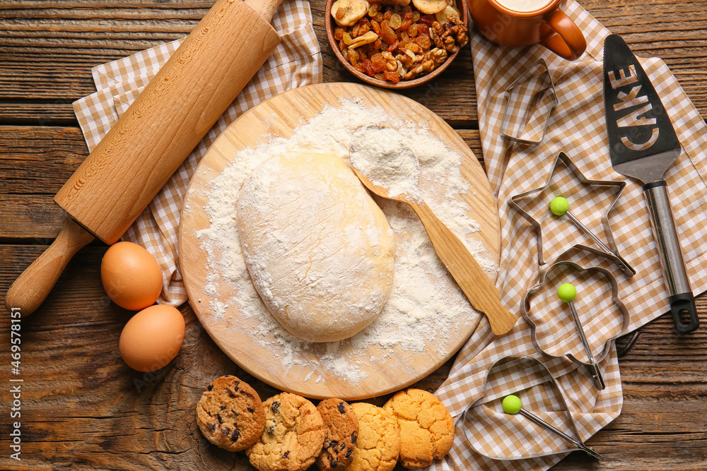 Board with fresh dough for preparing homemade cookies on wooden background