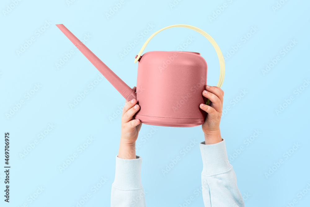 Pink watering can held by a raised hand