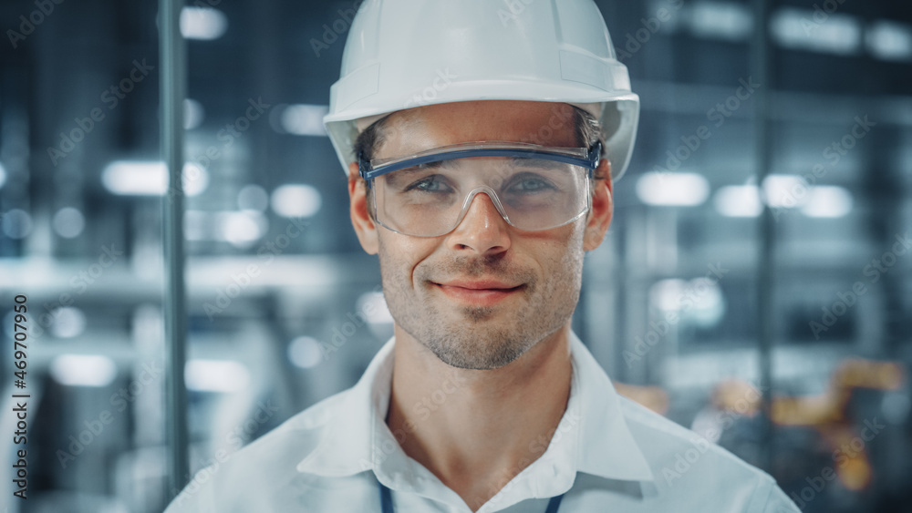 Portrait of a Young Handsome Confident Engineer Wearing Safety Goggles and White Hard Hat in Office 