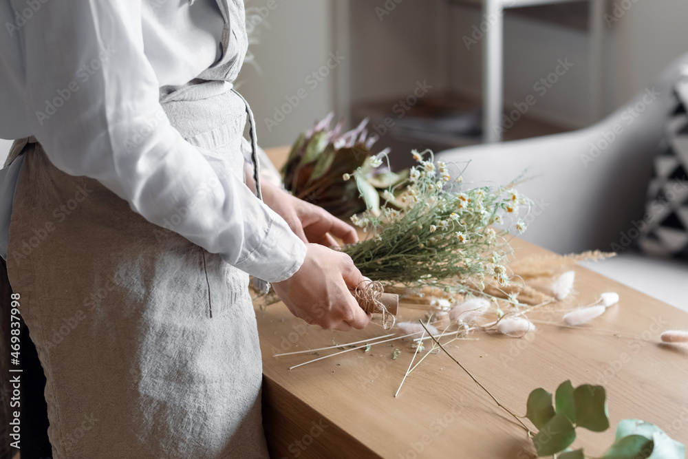 女花艺师在餐桌上用漂亮的干花制作花束