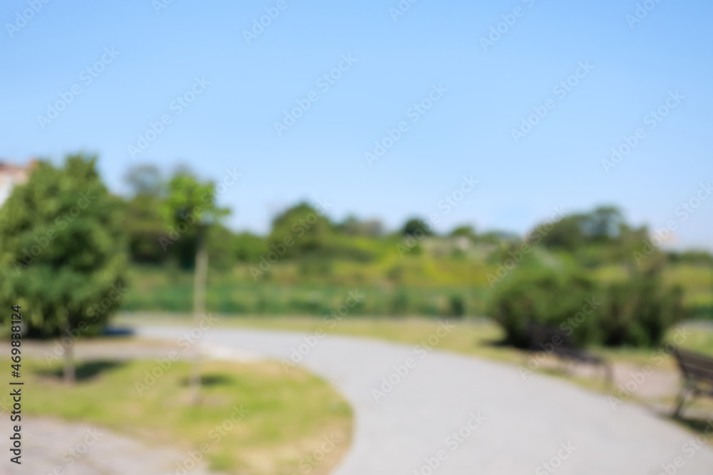 Blurred view of alley in city park on sunny day