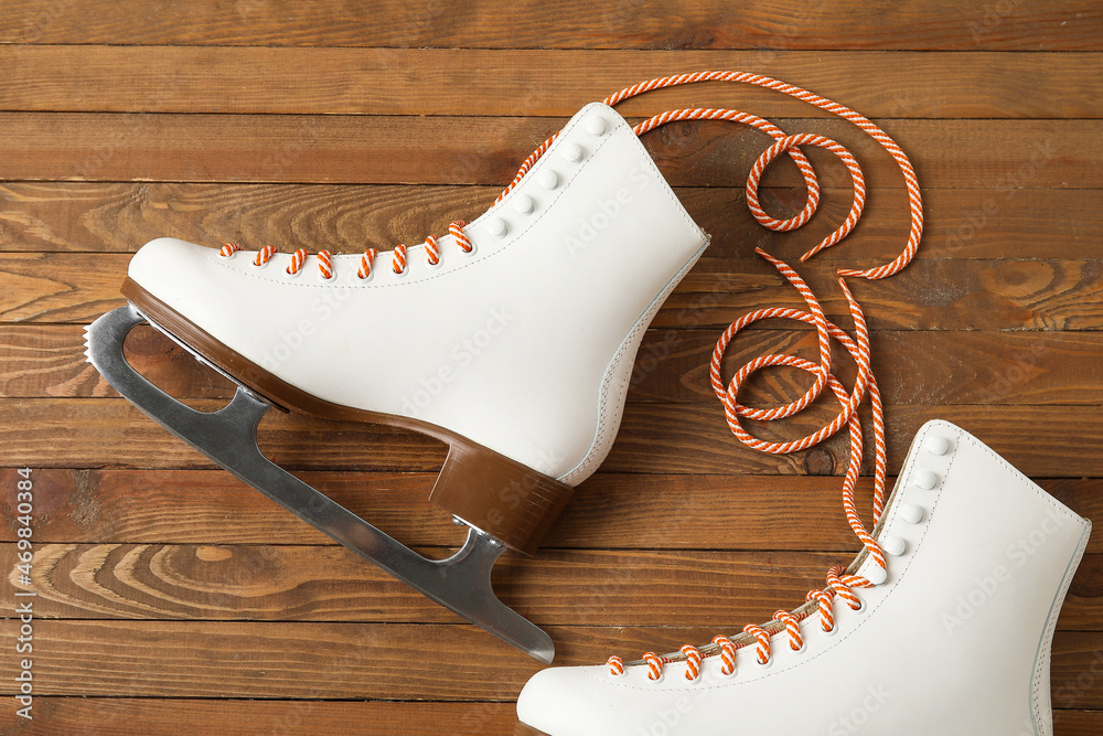 Pair of skates with untied laces on wooden background