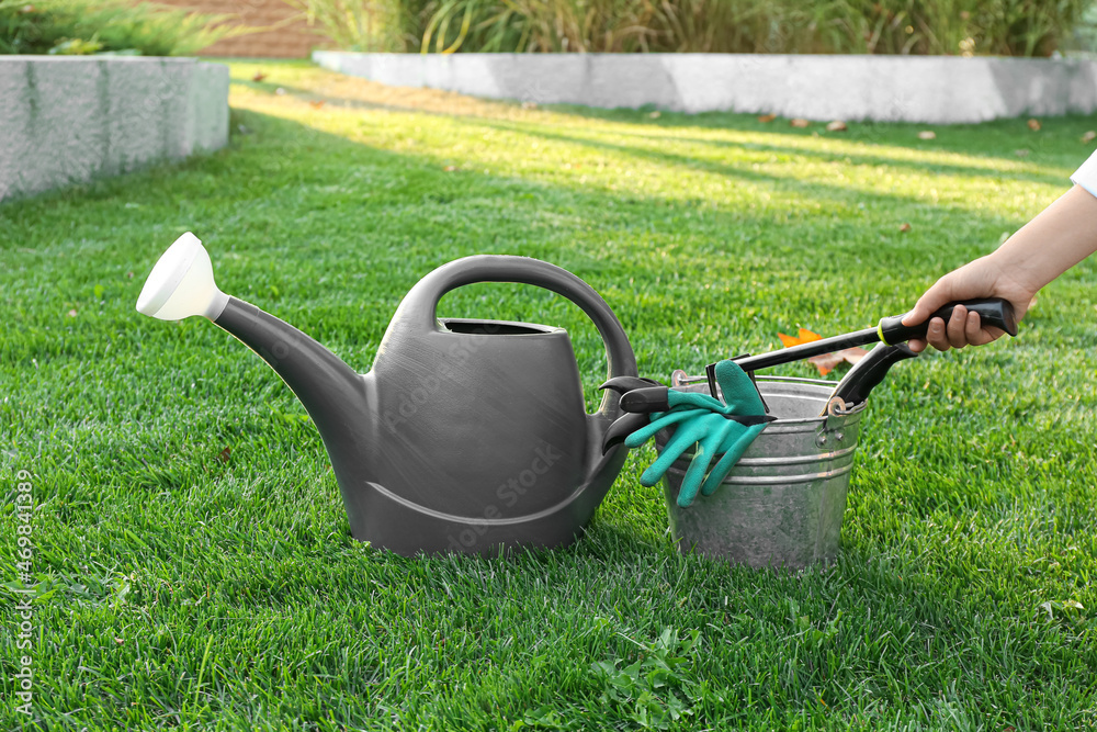 Woman putting gardening tools in bucket outdoors