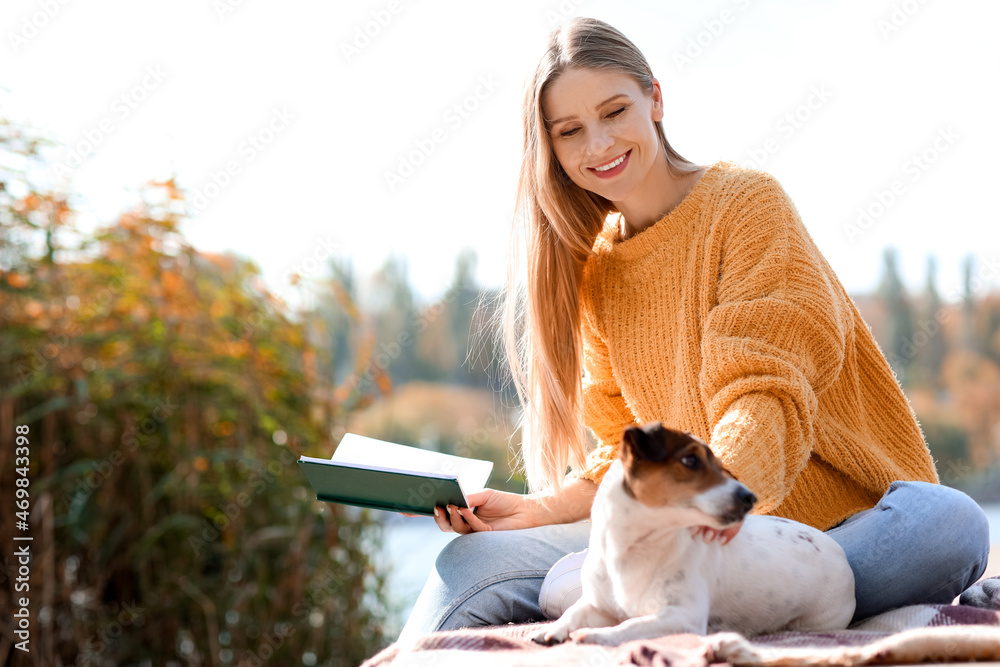 美丽的女人带着可爱的小狗在秋日读书