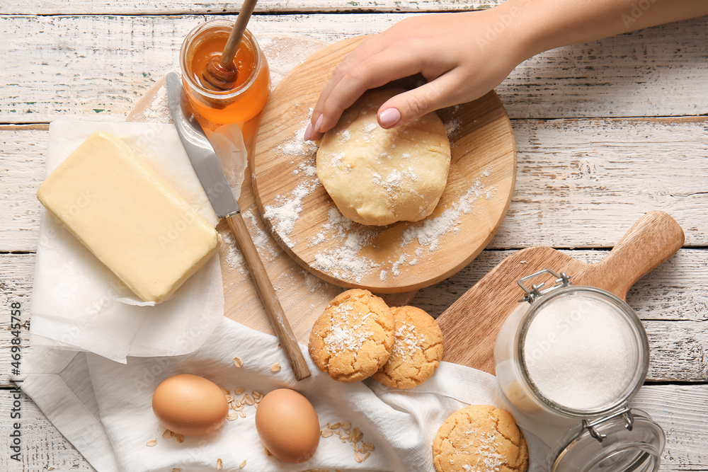 Woman preparing homemade cookies on white wooden background