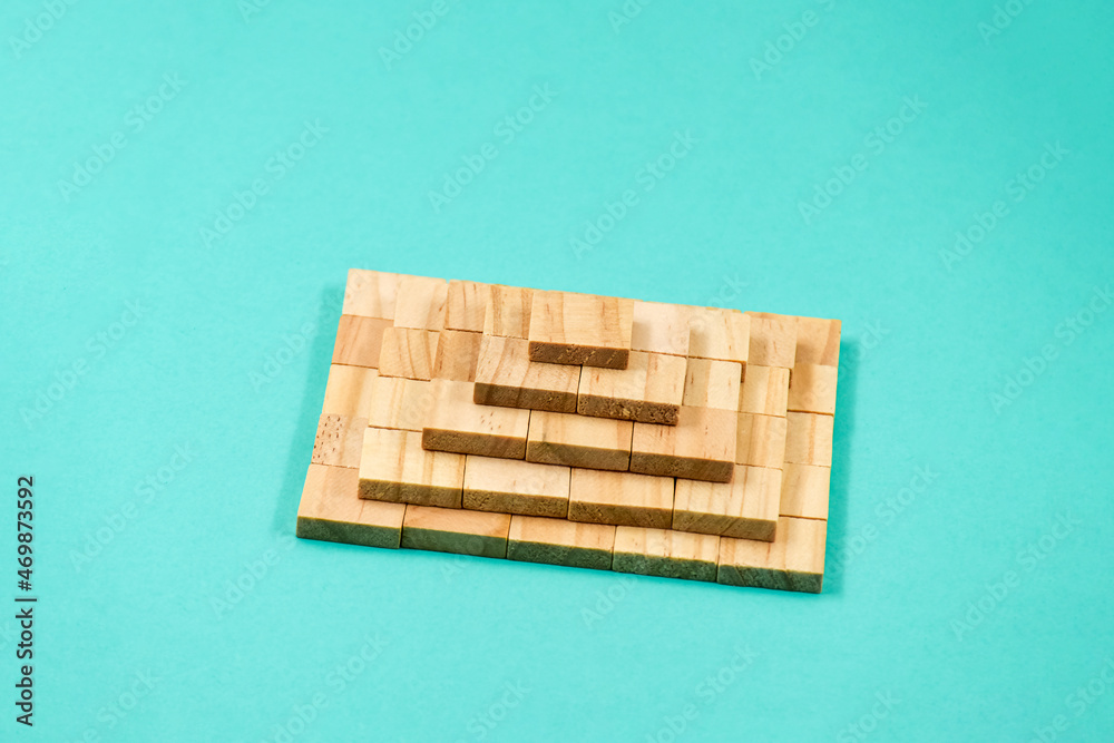 A pyramid stacked with wooden blocks on a blue paper background