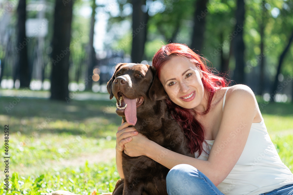 Young attractive woman hugs her dog in the park.