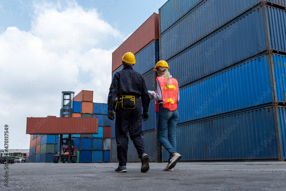 Industrial worker works with co-worker at overseas shipping container yard . Logistics supply chain 