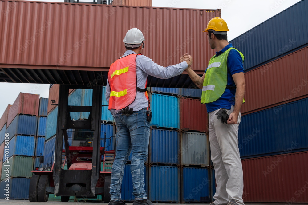 Industrial worker works with co-worker at overseas shipping container yard . Logistics supply chain 