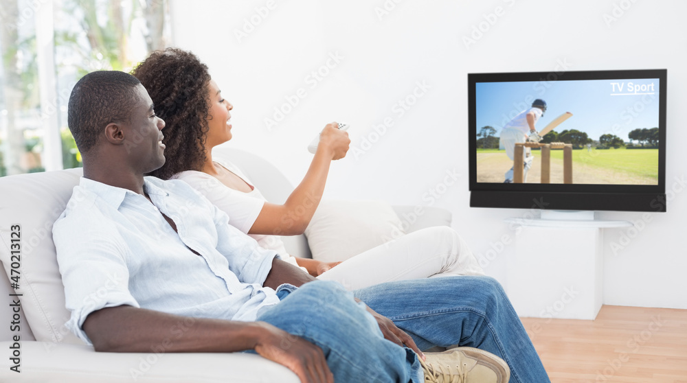 Side view of two friends sitting at home together watching cricket match on tv