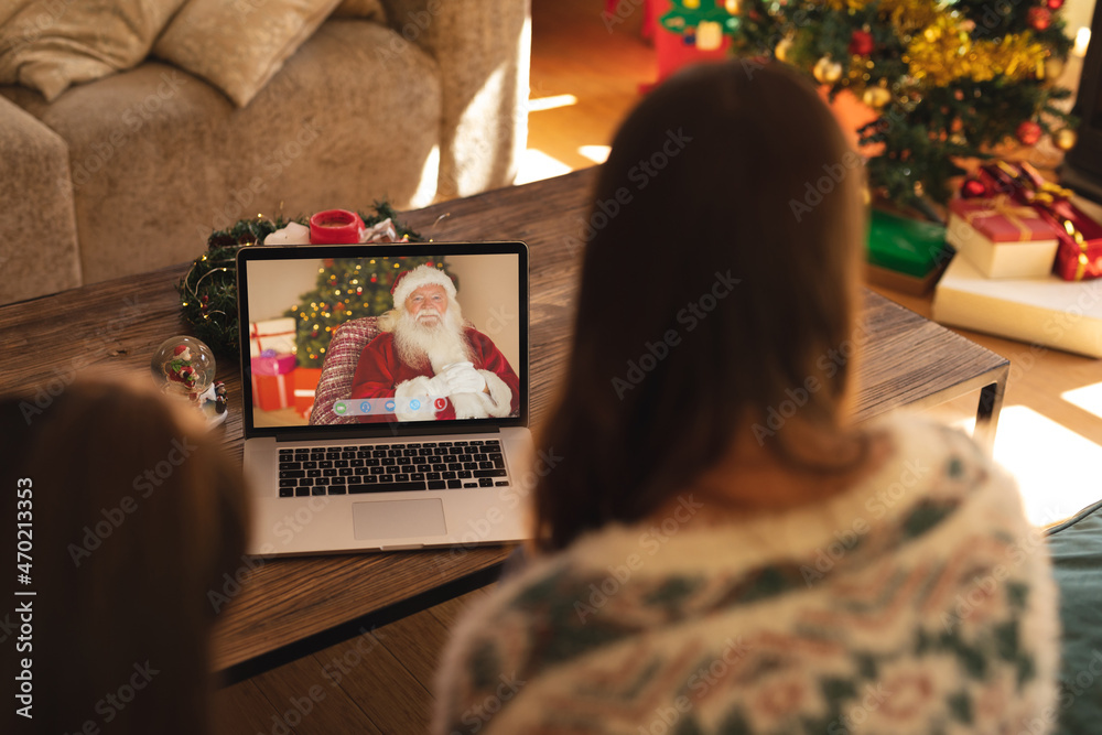 Mother and daughter making laptop christmas video call with smiling santa claus