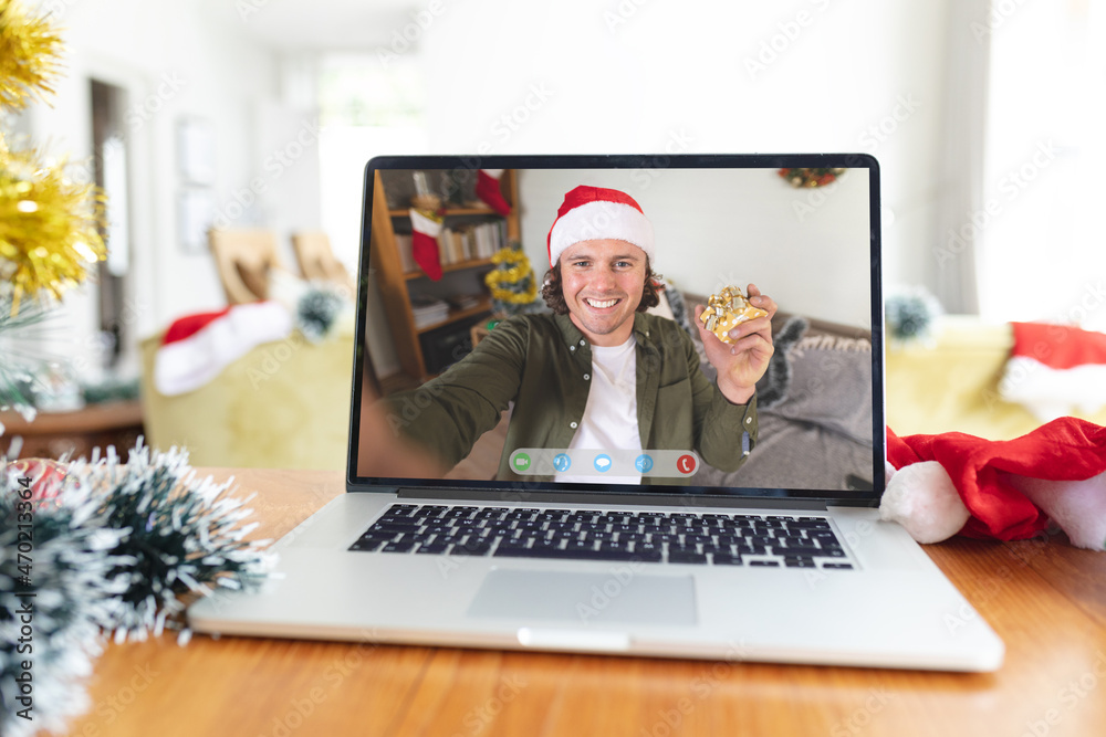 Smiling caucasian man in santa hat on laptop video call screen at christmas