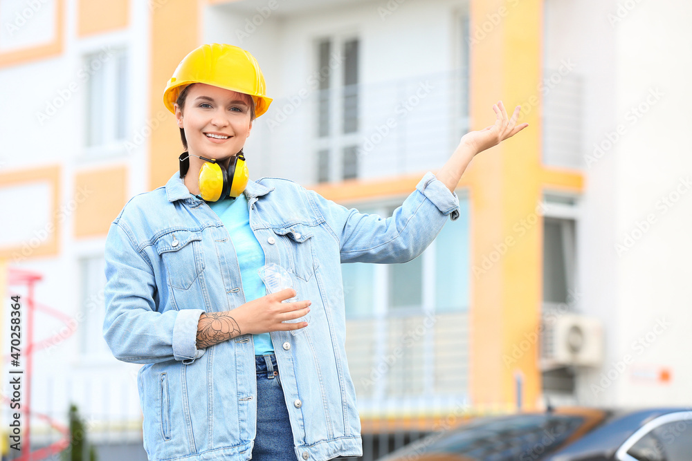 戴安全帽的女建筑工人在户外展示东西