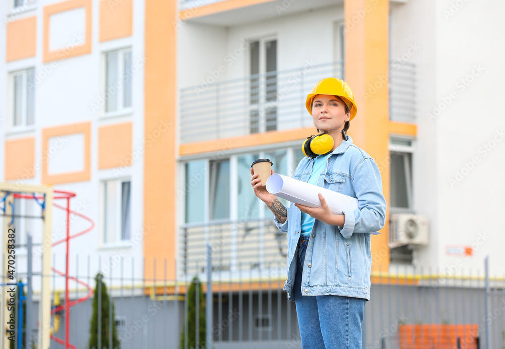 女建筑工人，有房屋平面图，在室外喝杯咖啡