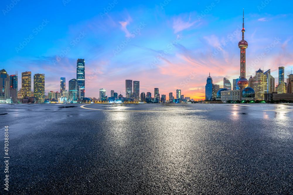 空旷的柏油路和现代化的城市天际线，日出时的上海建筑