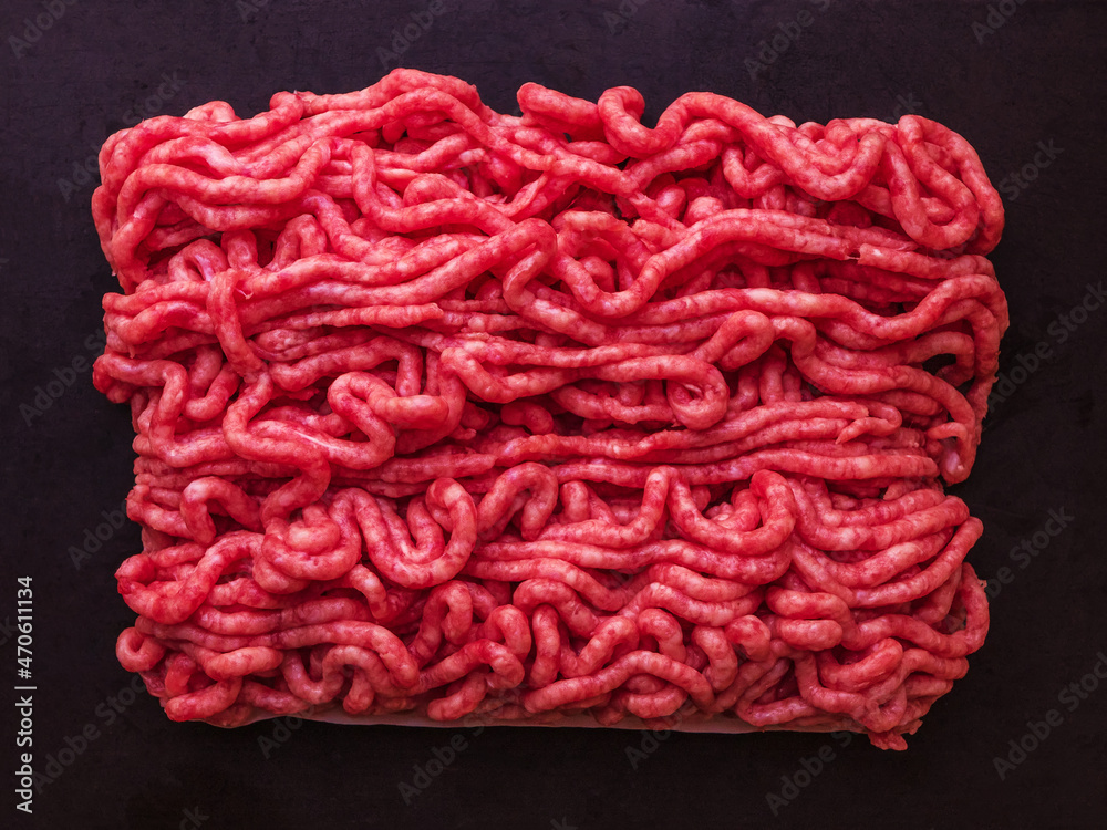 Raw minced meat briquette on a dark cement background. Top view.