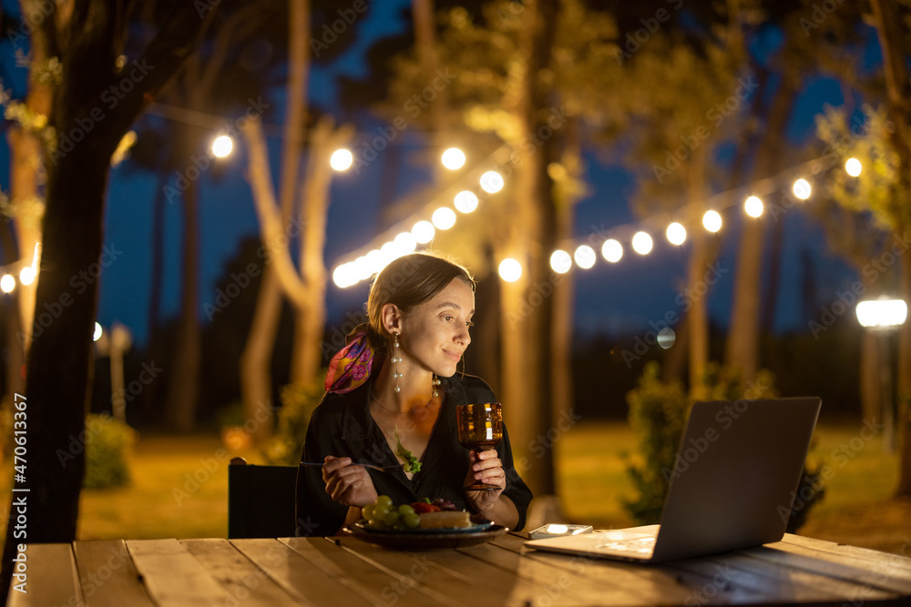 Caucasian woman watching something on laptop computer at evening time outdoors. Young woman sitting 