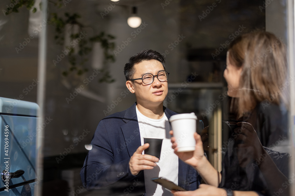 微笑的多种族夫妇在咖啡馆的桌子上喝咖啡。休息和休闲的概念。朋友的想法