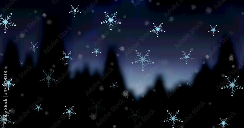 Image of snowflakes and falling snow in evening over silhouetted trees at christmas time