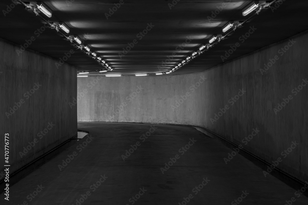 Highway road tunnel with light coming from the exit, Urban underground tunnel monochrome under pass.