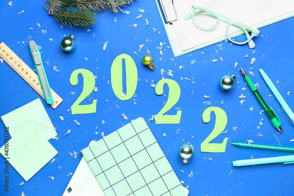 Figure 2022 with office supplies and decor on color background