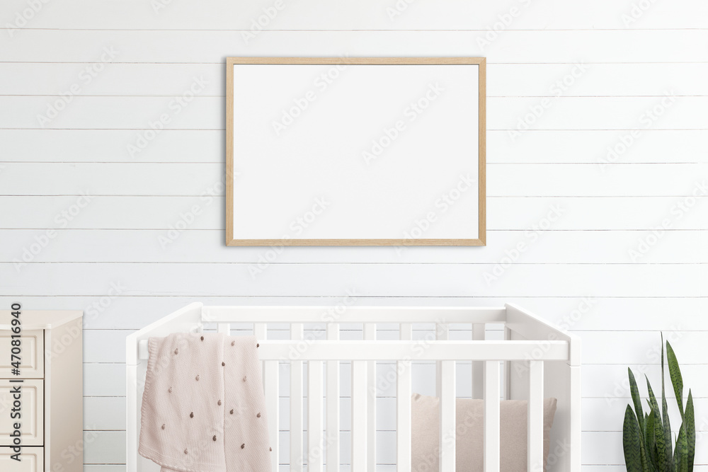 Blank picture frames hanging above a crib in a minimal nursery room