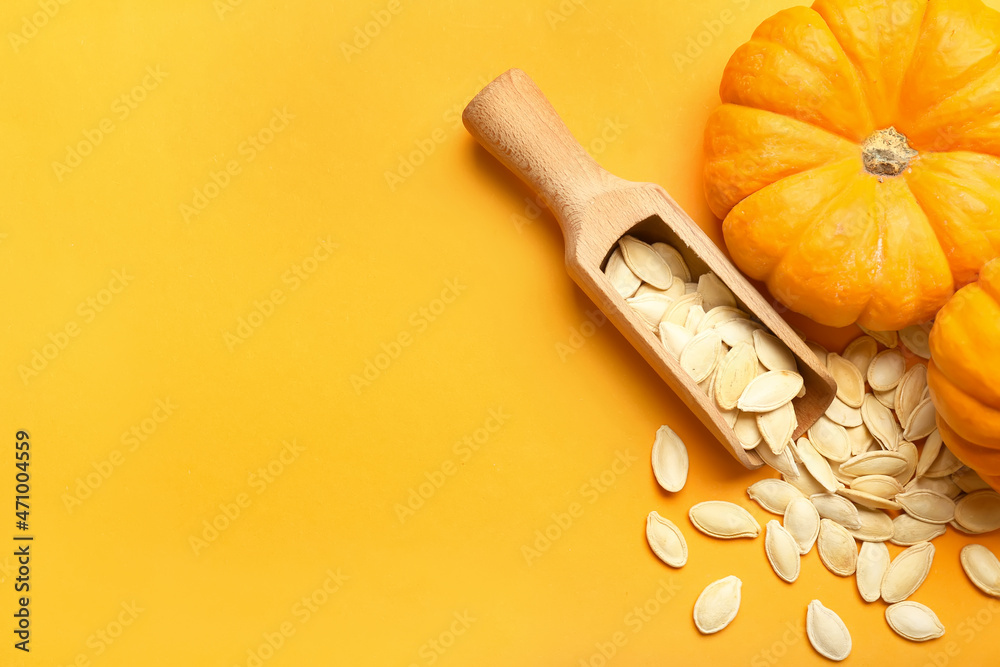 Scoop with natural pumpkin seeds and fresh vegetables on orange background