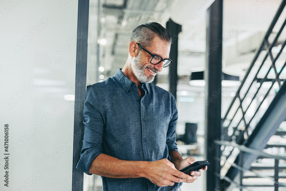 Cheerful businessman sending a text message in an office