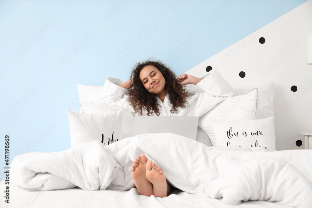 Morning of happy young woman with laptop sitting in bed