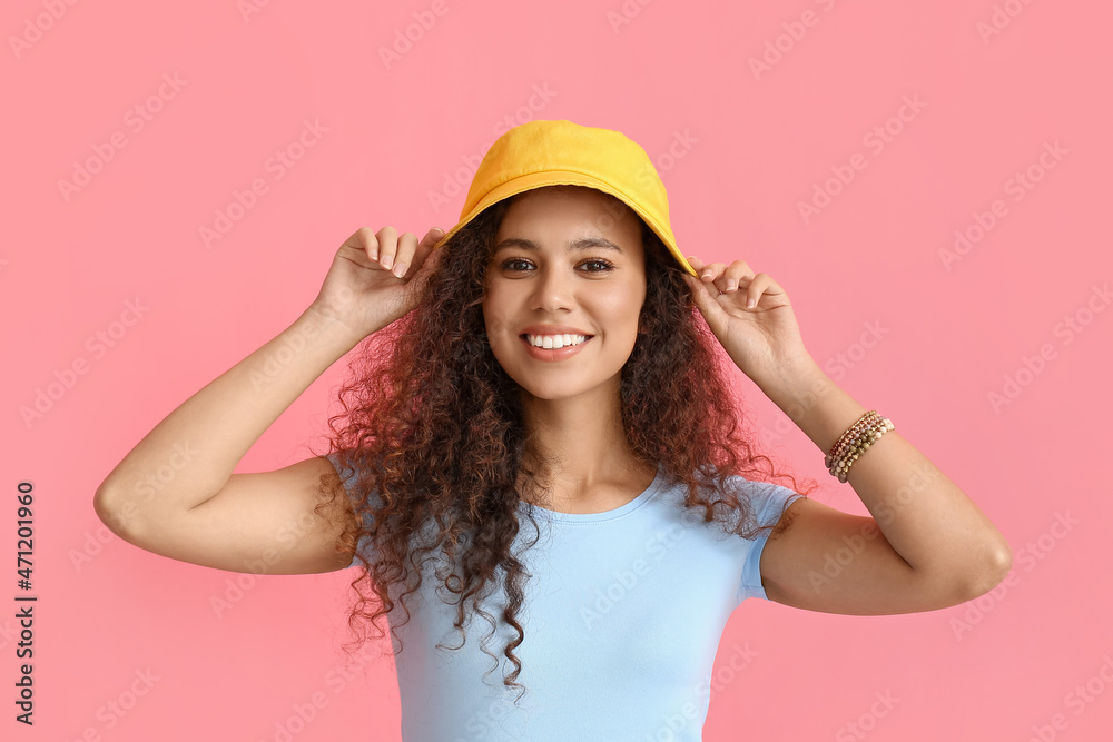 Beautiful African-American woman in stylish hat on color background