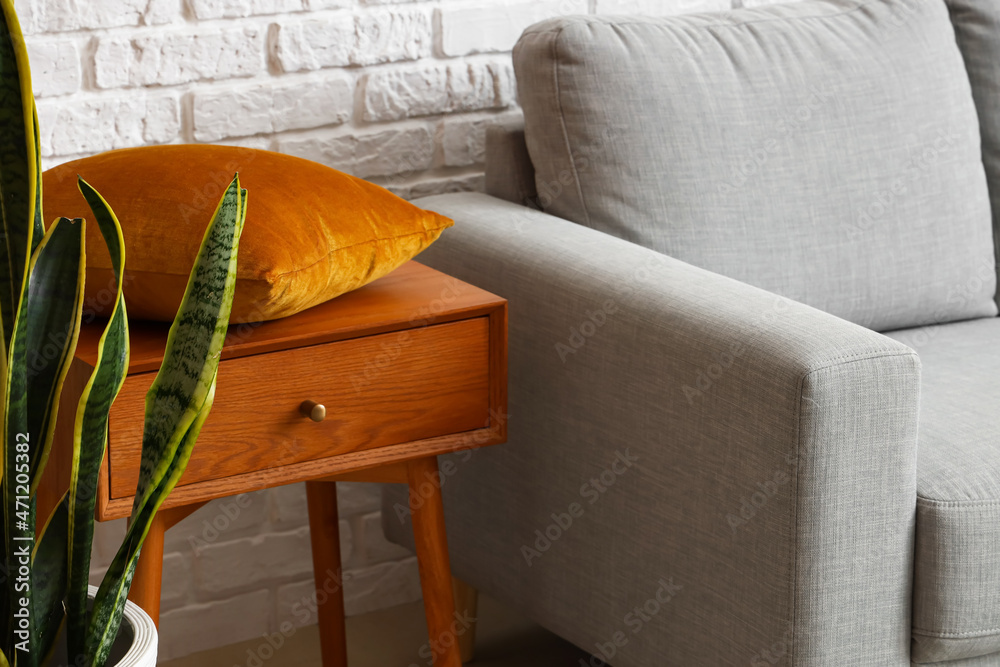 Wooden table with pillow near white brick wall