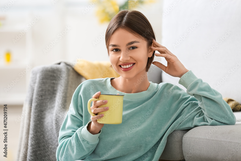 美丽的年轻女人在家里喝着美味的茶