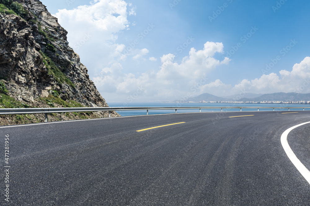 蓝天下的柏油路和山。大海背景下的公路和山。