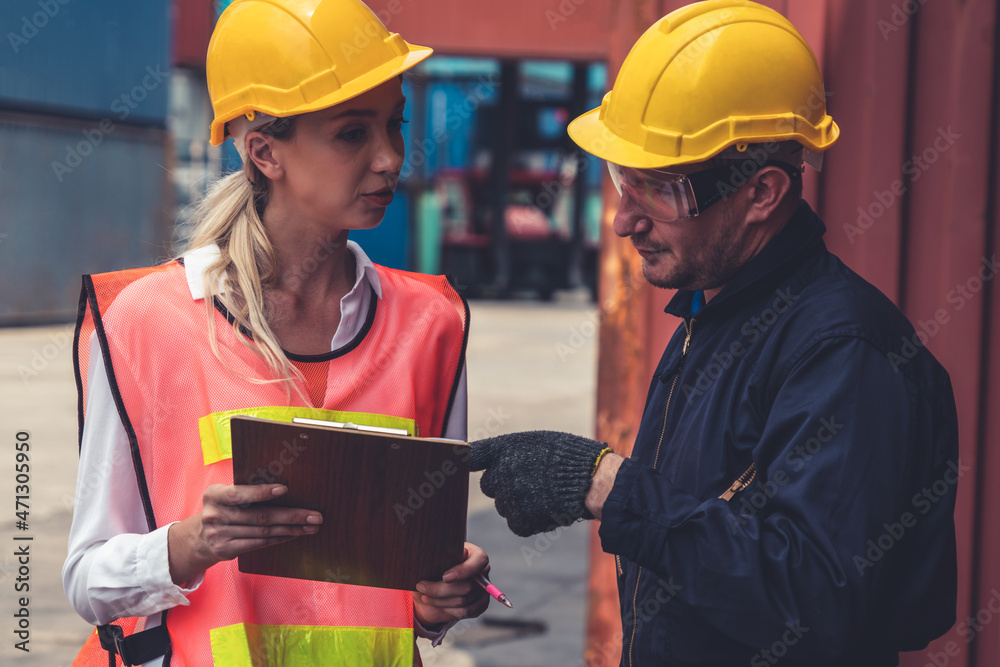 Industrial worker works with co-worker at overseas shipping container yard . Logistics supply chain 