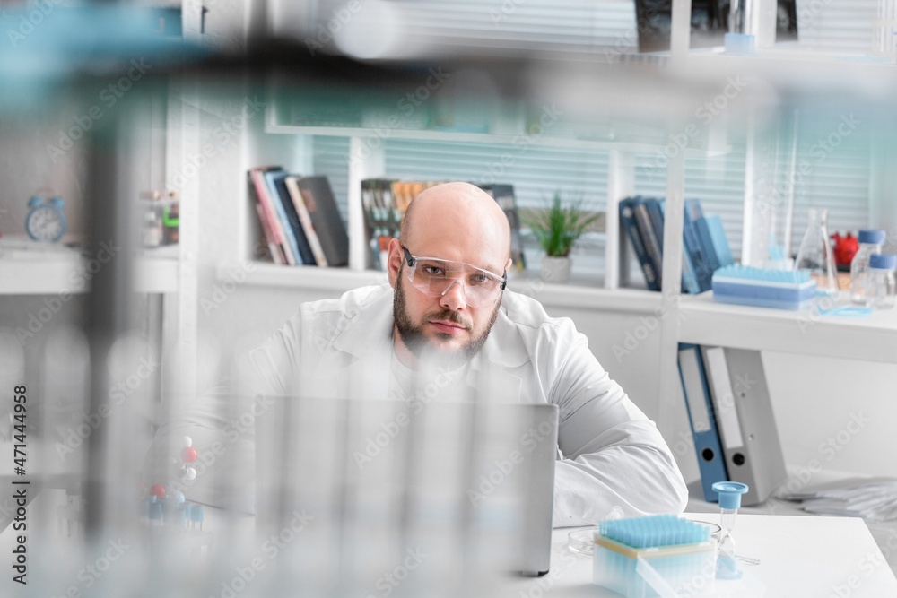 正在工作的男科学家。微生物学家是技术设备明亮实验室的橡胶手套