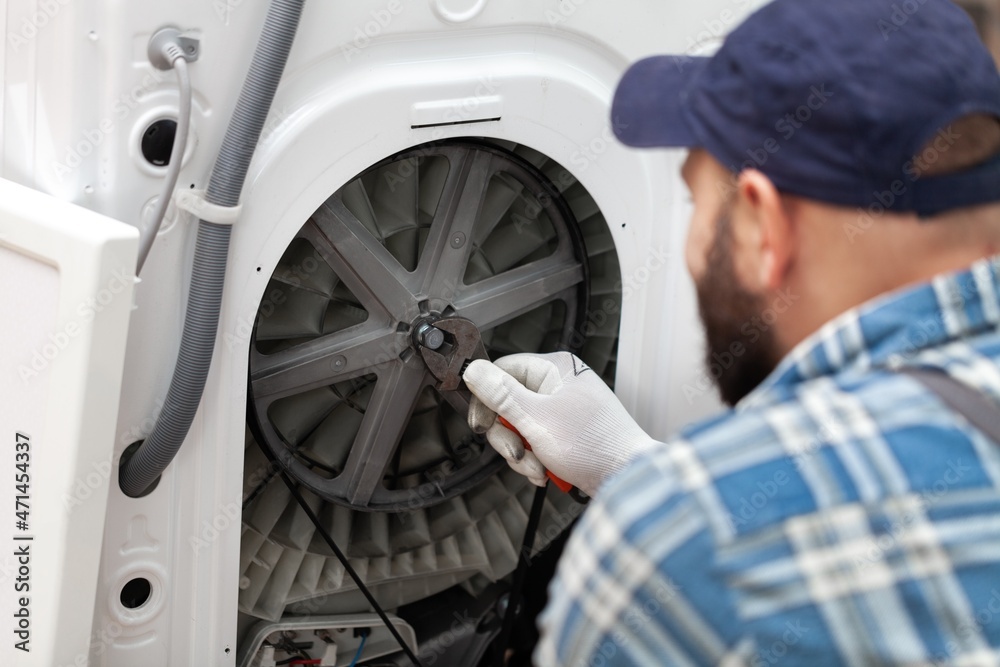 a man repairing a washing machine in cap