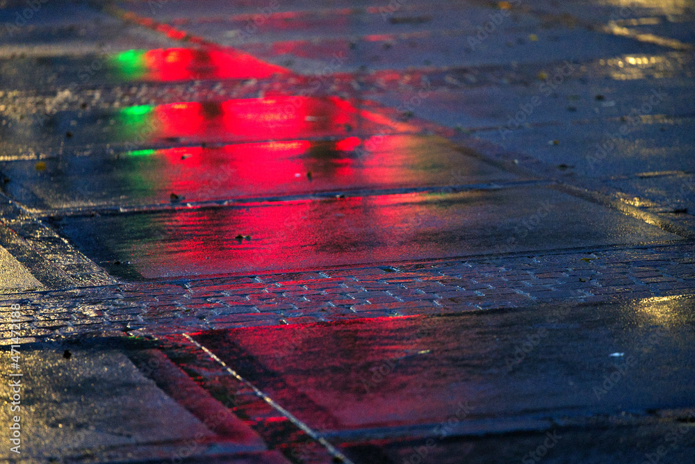 Close-up of wet square at City of Zürich with reflections of green and red lights on a rainy autumn 