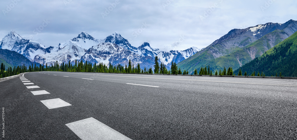 蓝天下的沥青路和雪山。公路和山脉背景。